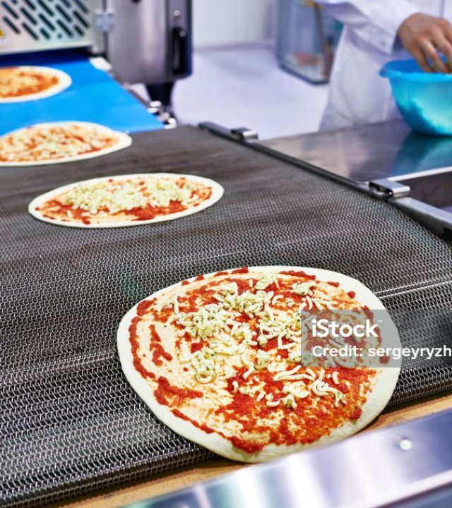 worker baker cook adds cheese to the pizza on the conveyor